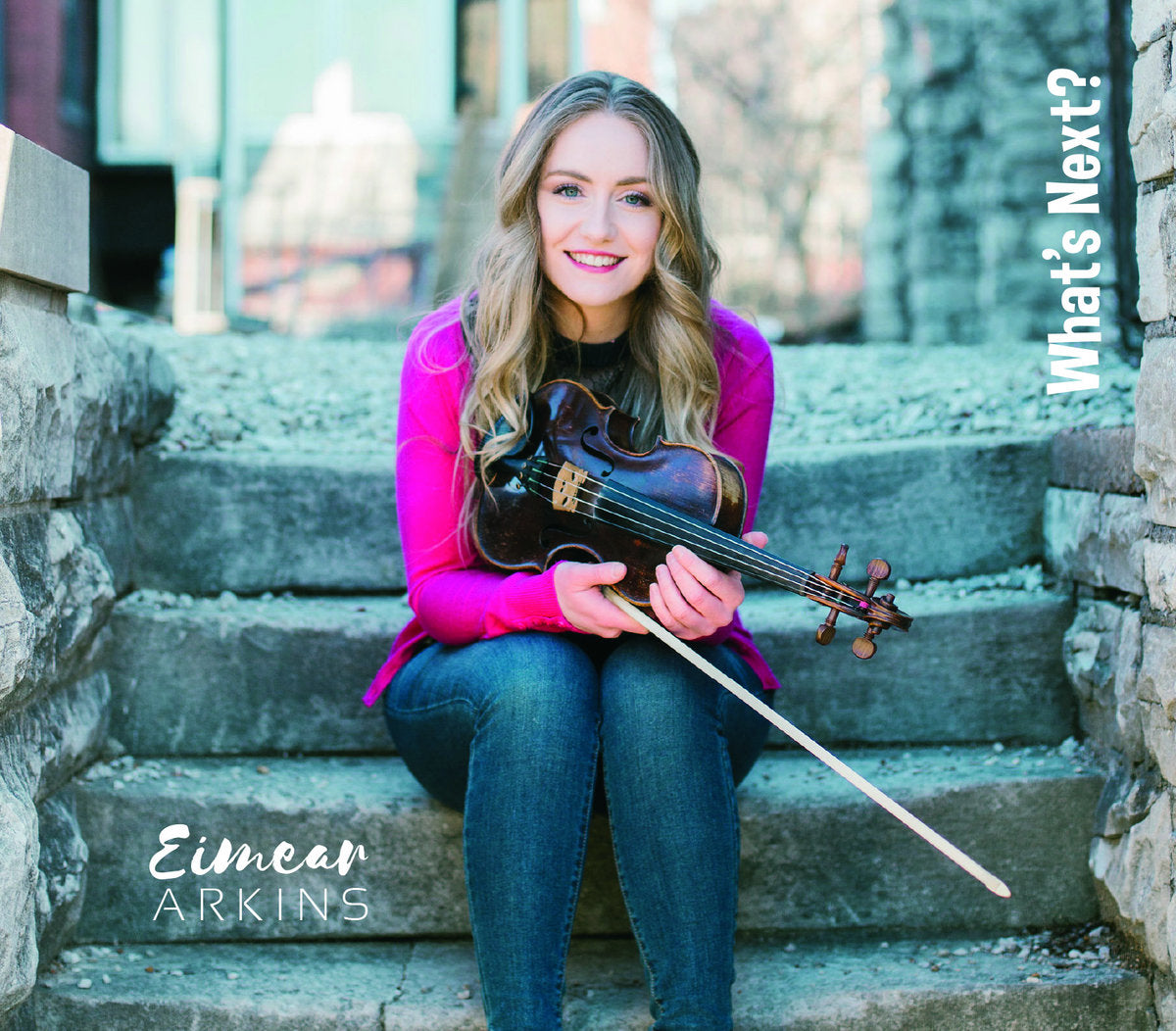 Eimear Arkins holds her fiddle while sitting on stone steps