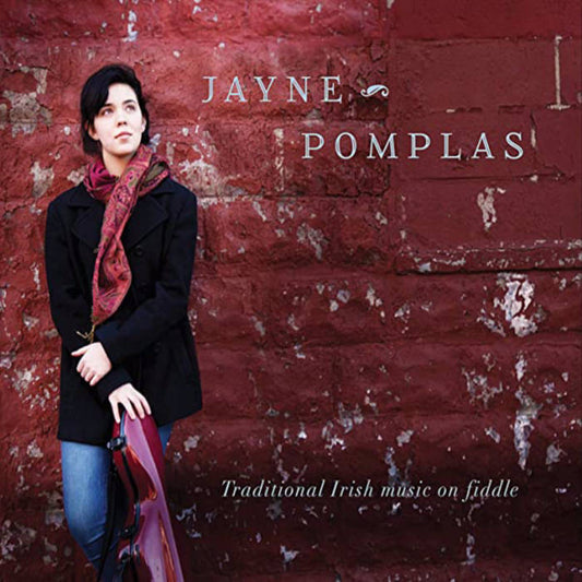 A girl with a black coat and red scarf leans against a red brick wall, with a fiddle case. Her name "Jayne Pomplas" appears over the album title, Traditional Irish music on fiddle