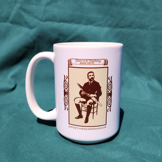 White mug with a graphic of a man playing uilleann pipes on a teal fabric background