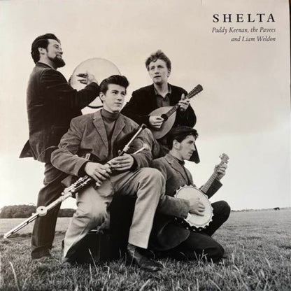 Album cover with a black and white photo of four musicians playing instruments on a grassy field, with 'Shelta' at the top.